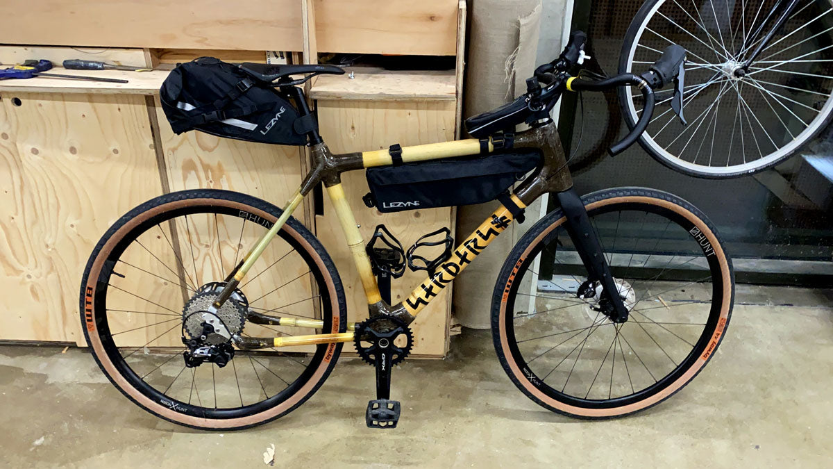 Jonathan's bamboo gravel bike with bikepacking saddle and frame bags and tan-wall tyres in a workshop