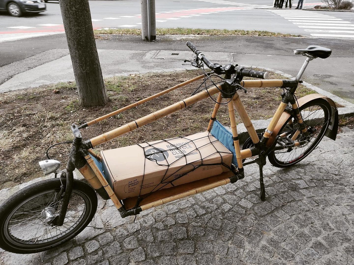 Bamboo cargo bike carrying a Bamboo Bicycle Club kit box strapped under a net on its front platform