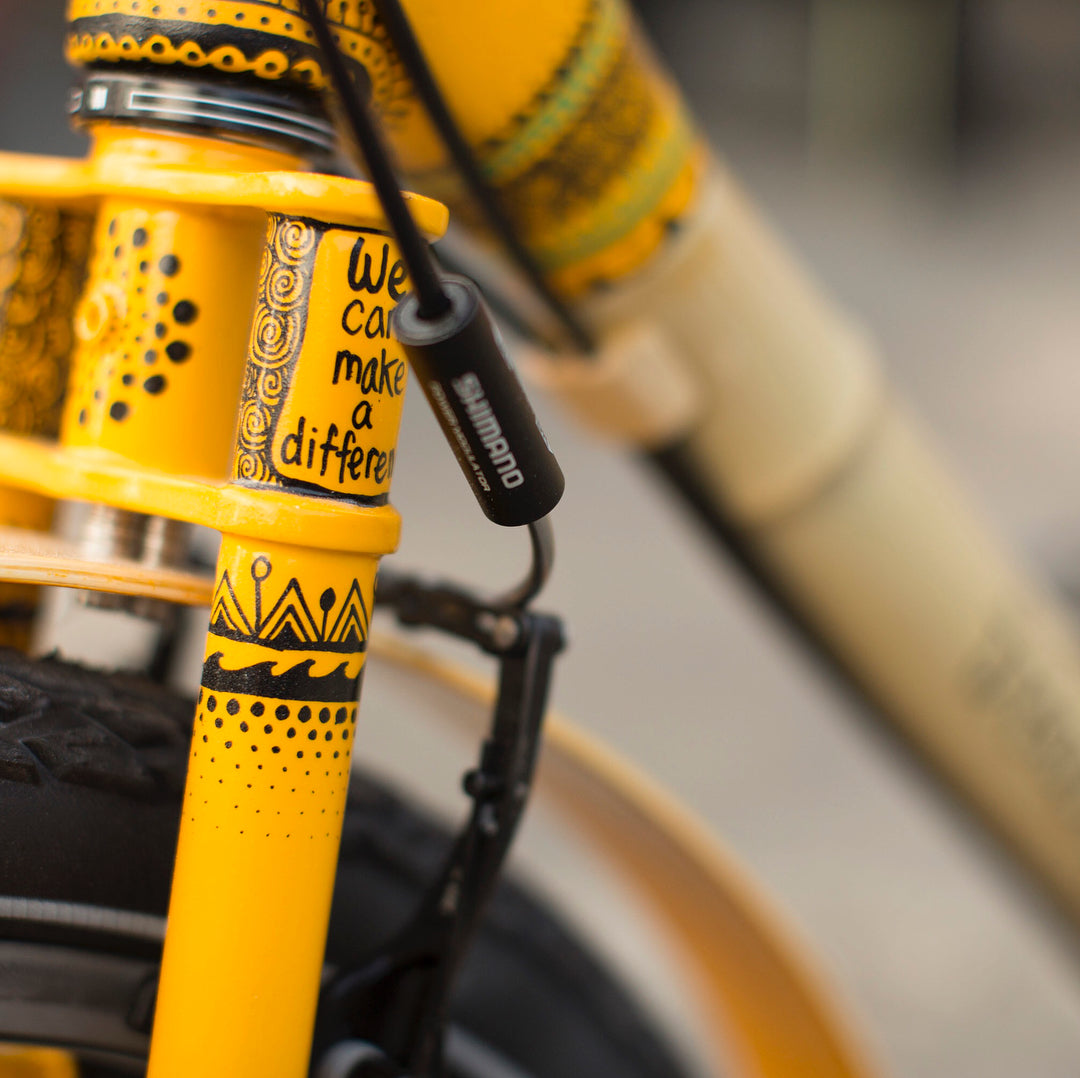 Close-up of Libby's yellow-painted fork and head tube, decorated with black hand-drawn patterns and lettering