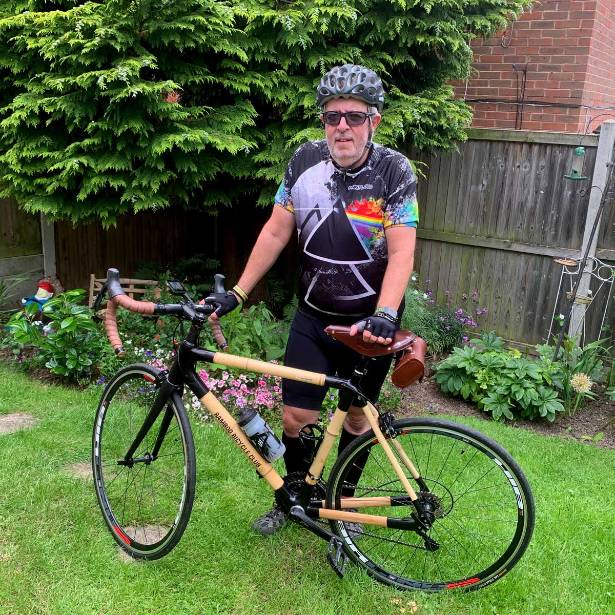 Ian's bamboo road bike with black joints and brown bar tape, held by a rider in a garden