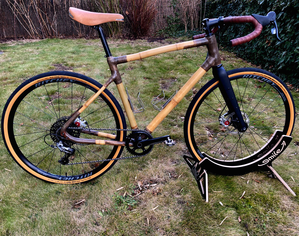 Georg's bamboo gravel bike with brown joints and tan-wall tyres on a display stand on a lawn