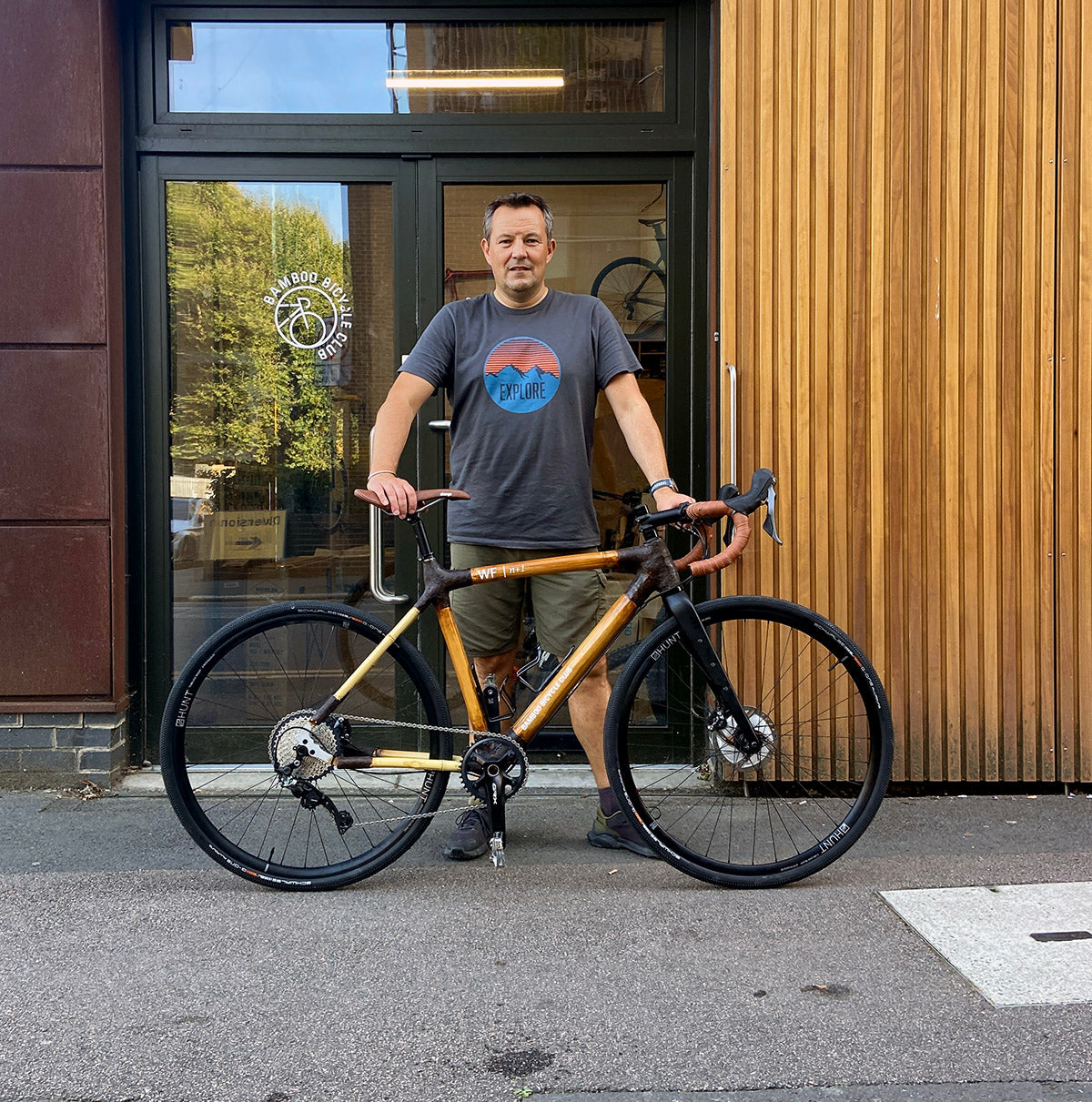 A person standing behind Will's finished bamboo gravel bike outside the Bamboo Bicycle Club workshop