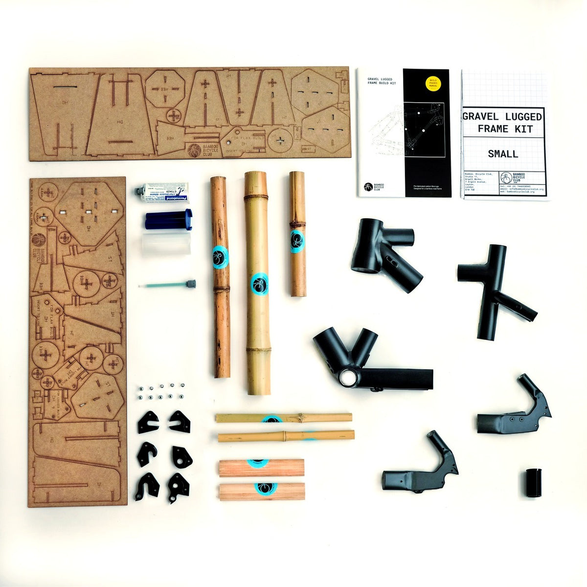 Gravel lugged frame kit laid out on white: bamboo tubes, black lugs, MDF jig sheets, adhesive and booklets