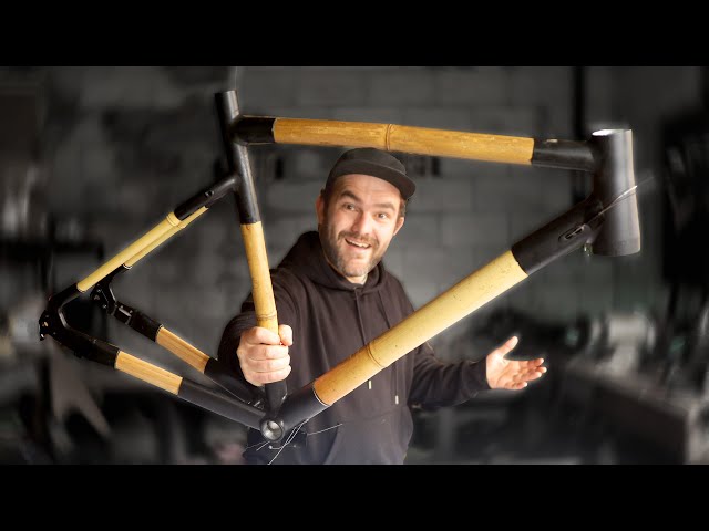 Presenter holding up a bamboo gravel frame with black lugs in a workshop