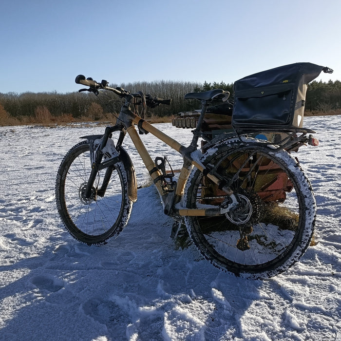 Shaun's bamboo mountain bike with a rack bag, standing in snow on a sunny winter day
