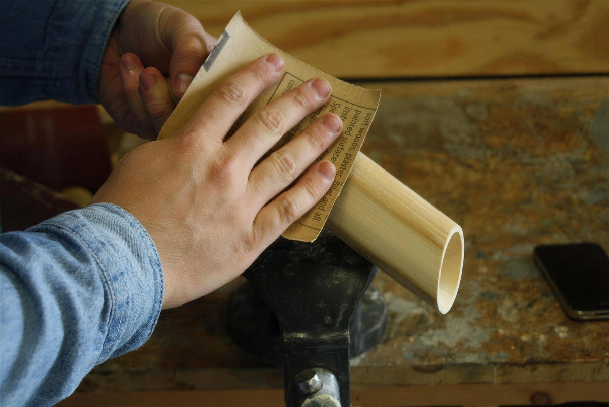 Sanding a bamboo tube in a vice to make a speaker