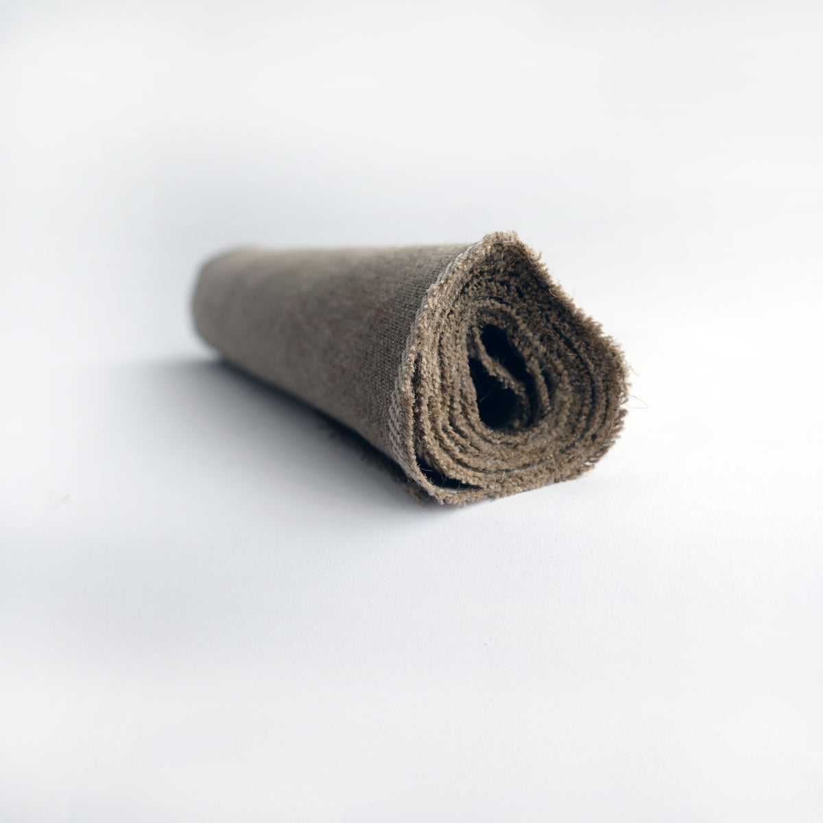 Rolled length of flax twill cloth on white, seen end-on to show the layers