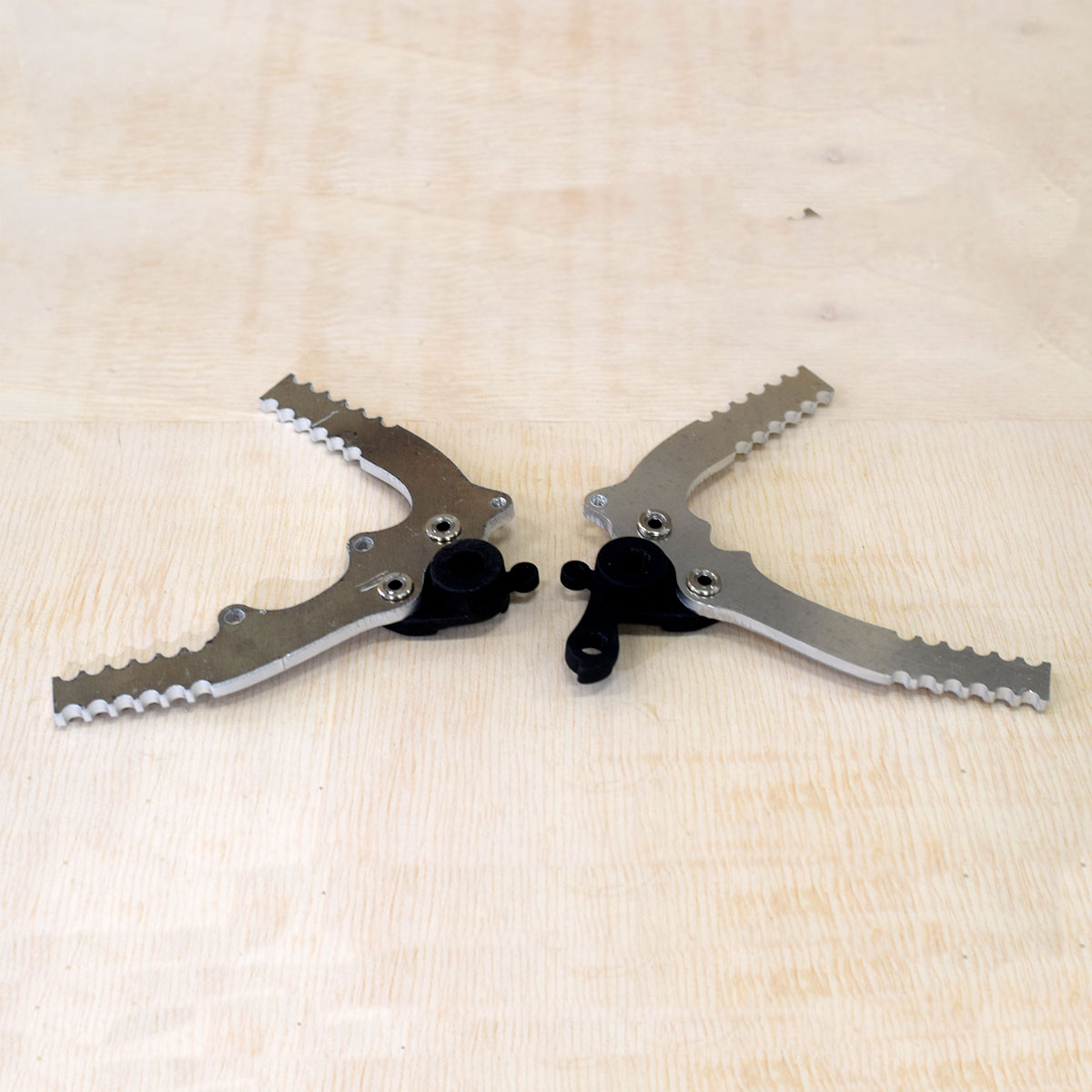 Pair of silver modular dropout plates with toothed edges and black thru-axle fittings on plywood
