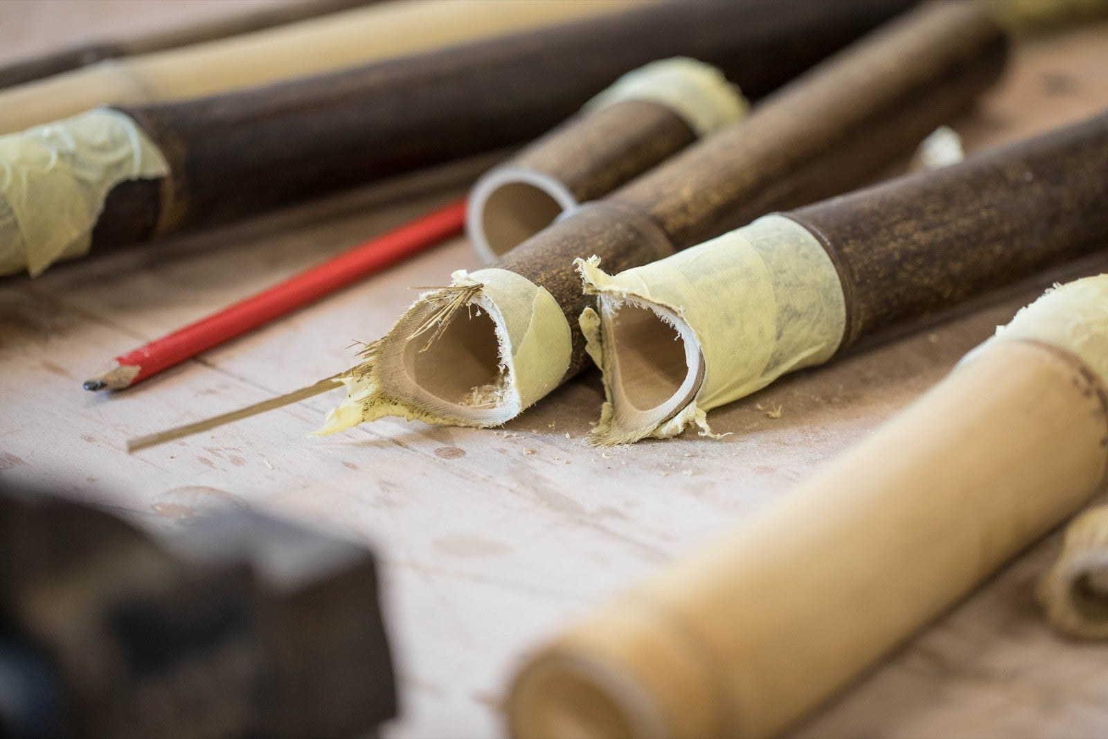 Cut and mitred bamboo tubes on a workbench beside a carpenter pencil