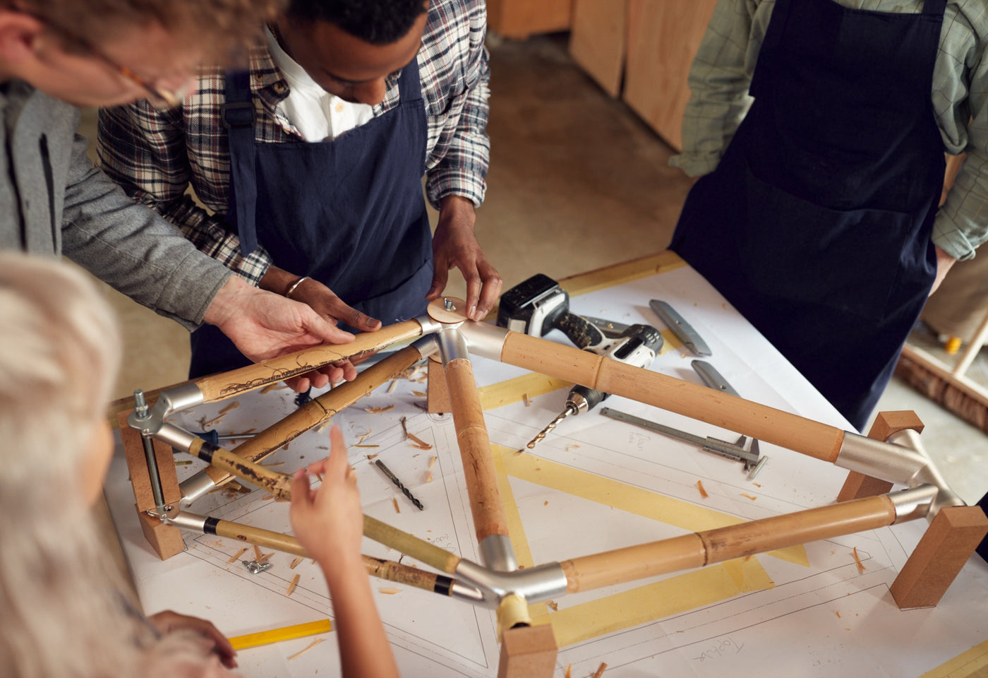 A team fitting bamboo tubes into a frame on the build table