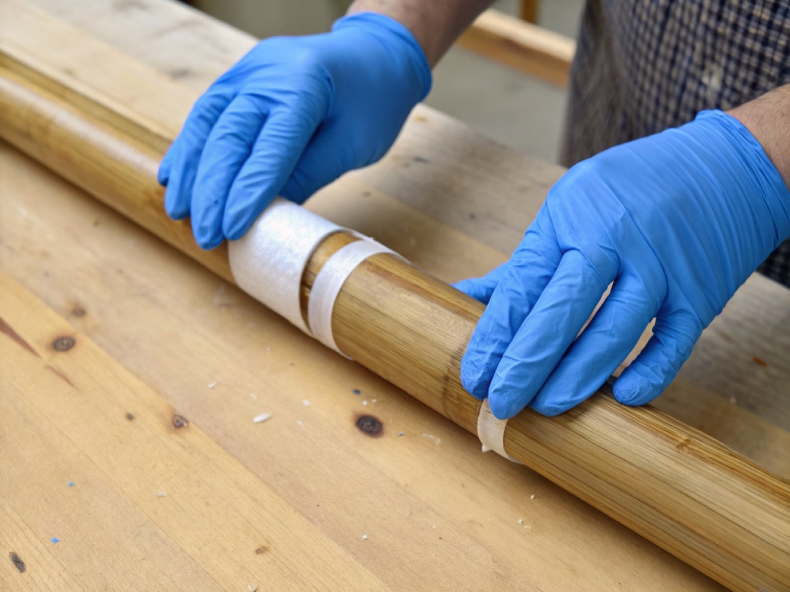 Gloved hands wrapping and binding a bamboo frame joint on the workbench
