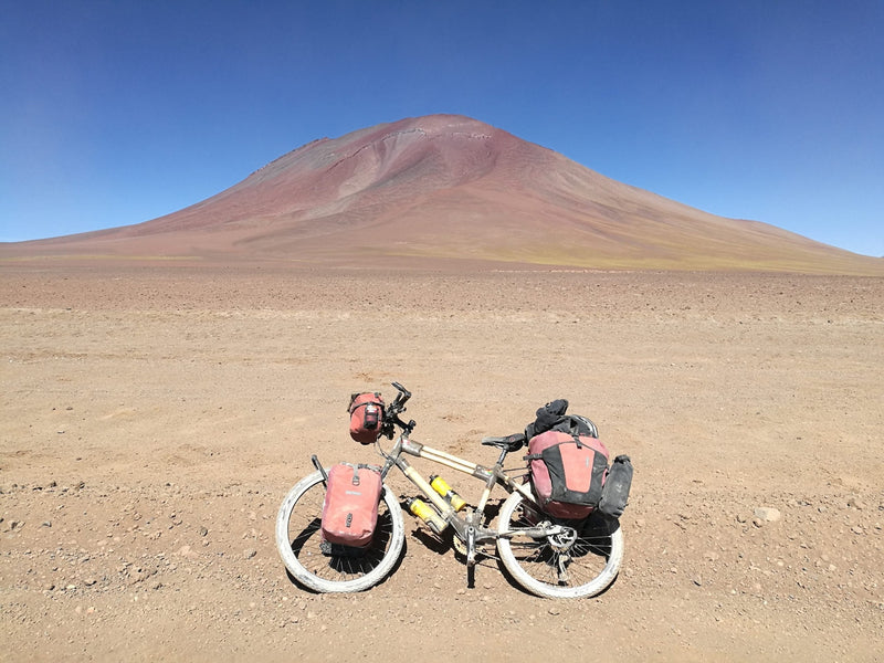 A bamboo touring bike loaded with panniers on a desert road in South America