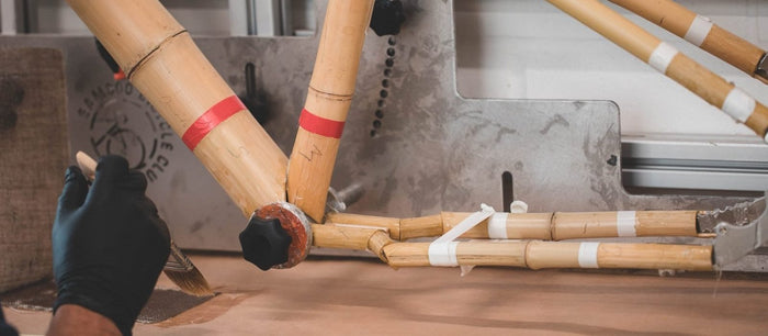 Gloved hands working bamboo tubes at the bench