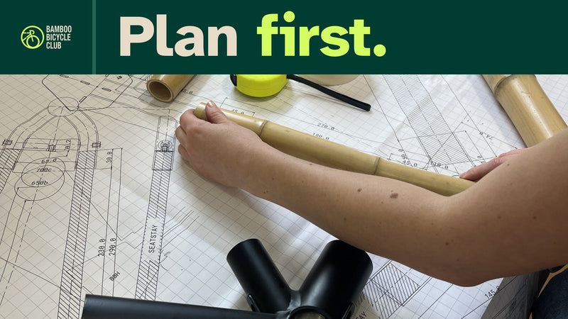 Plan first. Hands position a bamboo tube over a full-size frame drawing during an earlier BBC kit build; this photograph does not show the current R1K jig.
