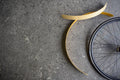 Wooden mudguard blanks curling beside a black rimmed wheel on a concrete floor