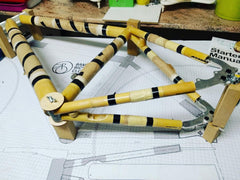 A gravel frame mid-build at home — tubes tacked on the jig over the full-size frame drawing