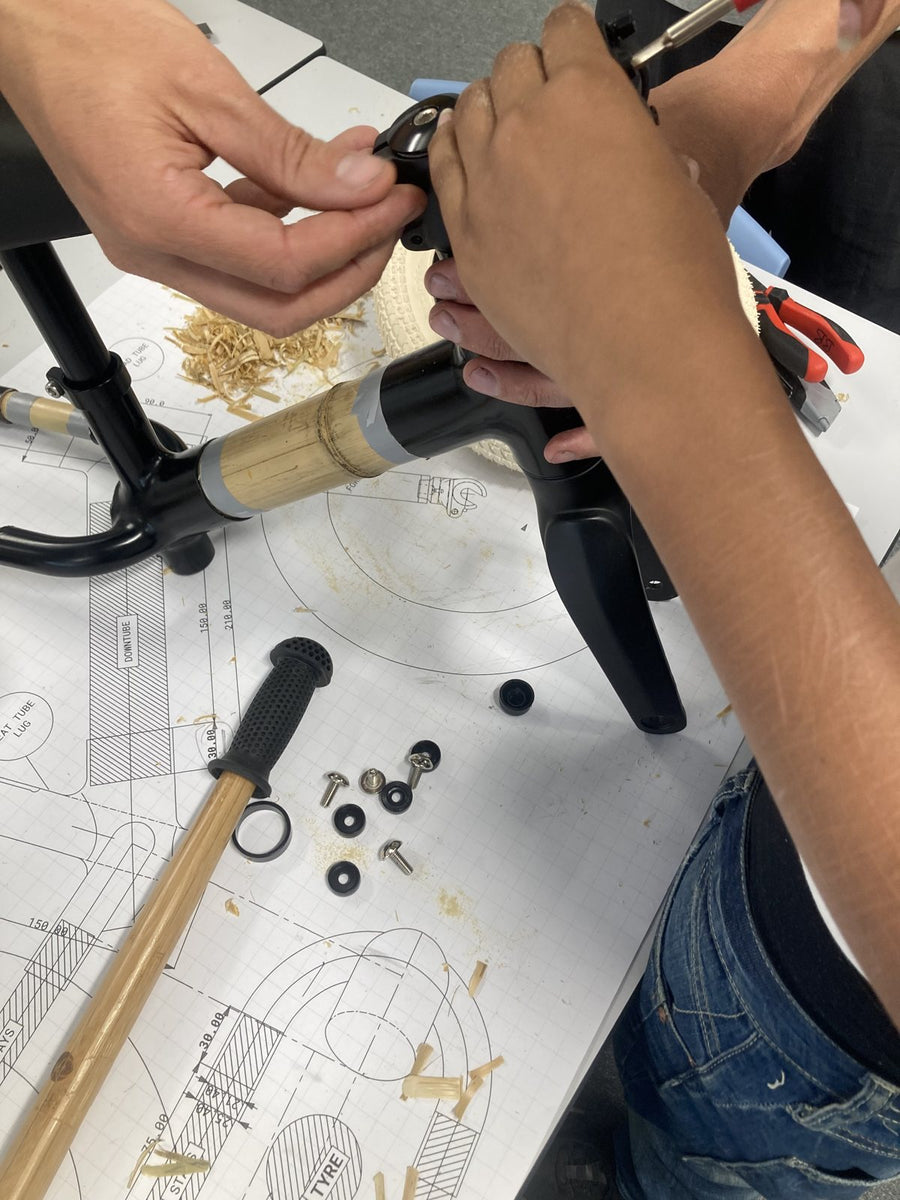 Hands fitting a handlebar grip onto a bamboo balance bike during the build