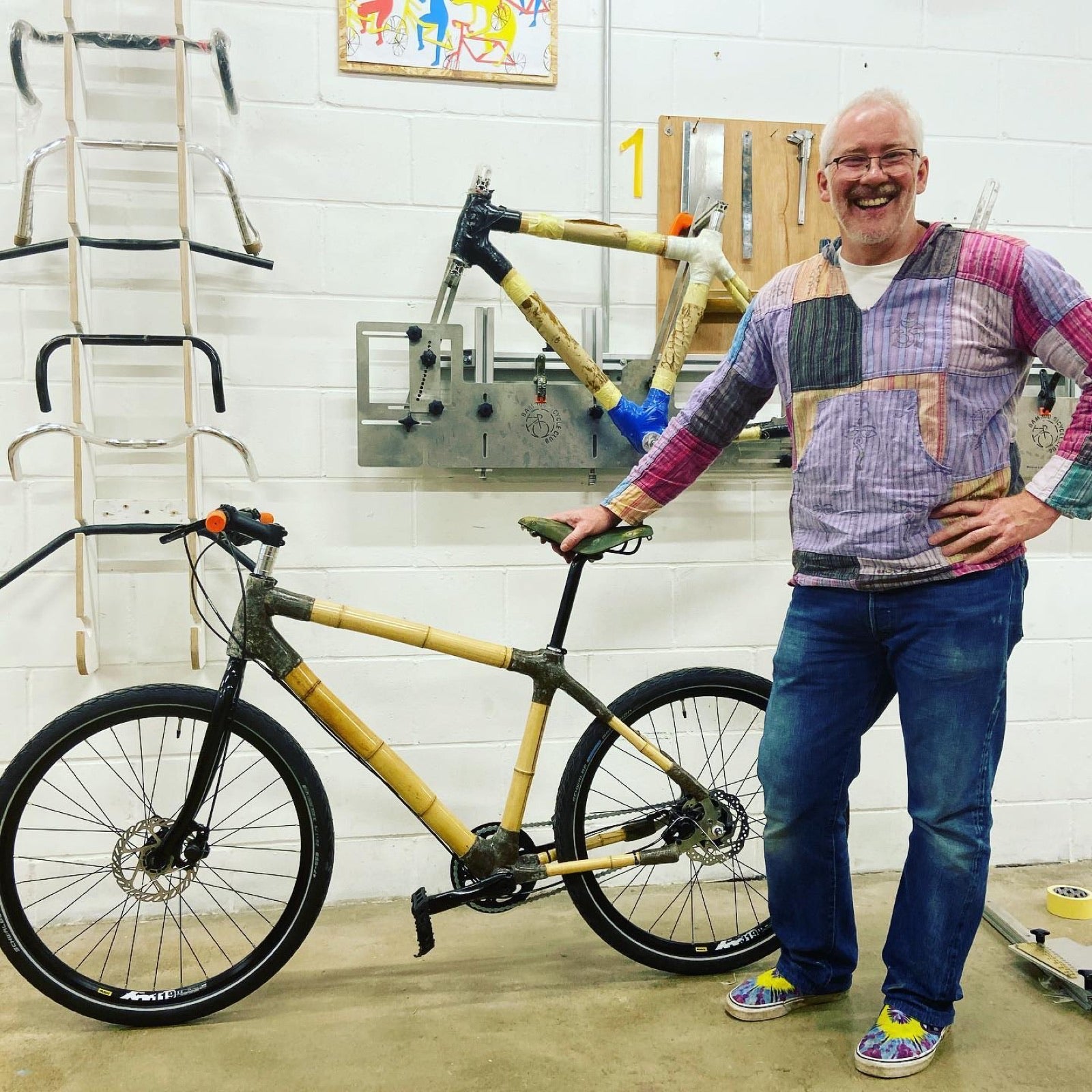 A first-time builder standing with the bamboo bike he made