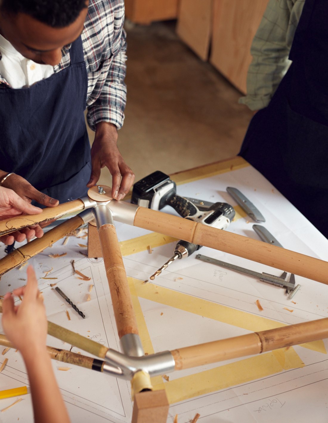 A team fitting bamboo tubes into a frame on the build table
